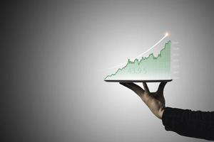 handelaar die tablet vasthoudt en technische grafiek aanraakt voor analyse van beursgegevens en speculatief investeringsconcept. foto
