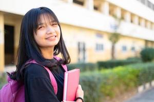 student jong meisje houdt roze boek en rugzak op school, terug naar school. foto
