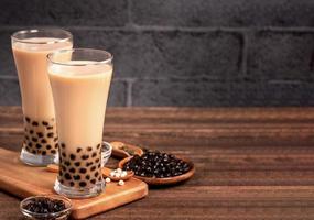 Heerlijke bubbelmelkthee met tapioca-parelbal in glas op houten tafel en donkergrijze bakstenen achtergrond, populair eten en drinken in taiwan, close-up foto