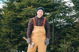 man houthakker met een bijl in zijn handen op een achtergrond van bos en bomen foto