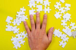 puzzel en handen op de gele conceptenachtergrond foto