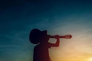 silhouet van een gitarist in de schaduw bij zonsondergang licht, silhouet concept. foto