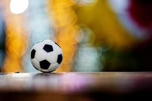 de voetbal is op een houten vloer geplaatst en heeft een onscherpe achtergrond met prachtige bokeh. foto