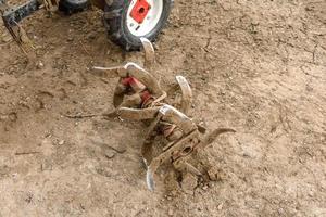 kleine landbouwtractor ploegt de grond, het werk van een achterlopende tractor foto