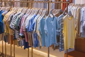 verscheidenheid aan kinderkleding die aan kledingrekken hangt te koop in de modewinkel in het winkelcentrum foto