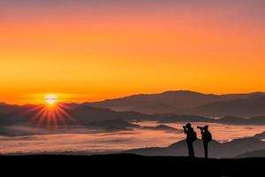 silhouet afbeelding van een reiziger man en vrouw fotograferen met zonsopgang in de ochtend op bergen natuurlijke achtergrond. foto