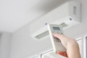 hand met afstandsbediening gericht op airconditioner foto