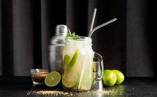 frisse zomerse caipirinha-cocktail op een zwarte gordijnachtergrond foto