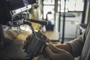 barista stomende melk voor warme cappuccino met machine foto