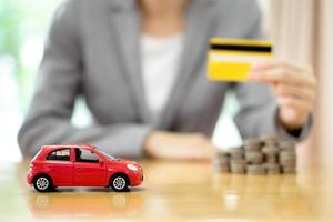 zakenvrouw hand creditcard, een speelgoedauto en een stapel munten foto