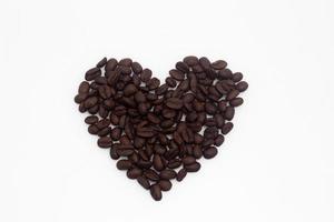 koffiebonen gerangschikt in de vorm van een hart op een witte achtergrond foto