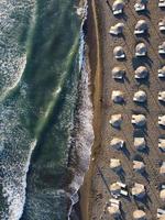 uitzicht van bovenaf, prachtige luchtfoto van een geweldig leeg strand met witte parasols en turquoise helder water met golven. foto