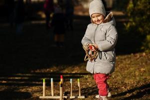 babymeisje speelt een spel gooien ring gooien buiten. foto