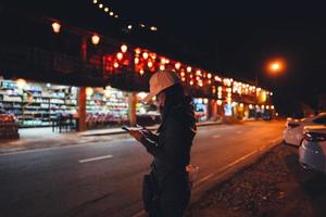 Aziatische volwassen vrouw die 's nachts mobiele telefoon gebruikt om taxi te bellen. foto