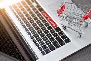 winkelwagen of trolley op laptop met tekst online winkelen, netwerkmarketing bedrijfsconcept foto