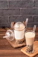 afhalen met wegwerp item concept populaire taiwan drinken bubble melk thee met plastic beker en stro op houten tafel achtergrond, close-up, kopieer ruimte foto