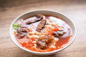 rundvlees noodle ramen maaltijd met tomatensaus bouillon in kom op lichte houten tafel, beroemde Chinese stijl eten in Taiwan, close-up, bovenaanzicht, kopieer ruimte foto