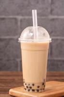 afhalen met wegwerp item concept populaire taiwan drinken bubble melk thee met plastic beker en stro op houten tafel achtergrond, close-up, kopieer ruimte foto