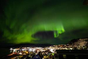 mooie aurola noorderlicht over de stad cityscap. noorderlicht in zuid kitaa qaqortoq groenland foto
