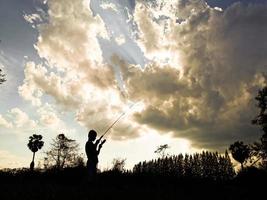 silhouet van een kind dat de gelukkige tijd van kinderen vist midden in de natuur bij zonsondergang foto