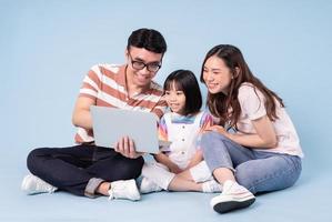 afbeelding van jonge Aziatische familie met behulp van laptop op blauwe achtergrond foto