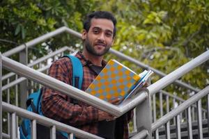 een jongen die boeken heeft, probeert zijn boek te lezen op de universiteitscampus student met boekenafbeeldingen foto