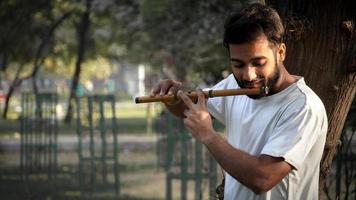 bansuri-speler die muziek speelt in de zon in het park - Indiase fluitspeler foto