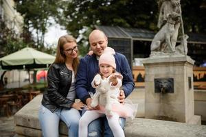 ouders en hun dochter zitten op de trappen van een oude kerk. foto