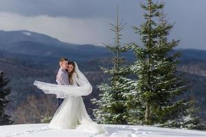 de bruidegom leidt zijn bruid bij de hand naar een eenzame oude beuk. winterse bruiloft. plaats voor een logo. foto