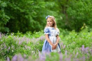 portret van een klein schattig meisje verkleed als Alice. gestileerde fotoshoot in de natuur. foto