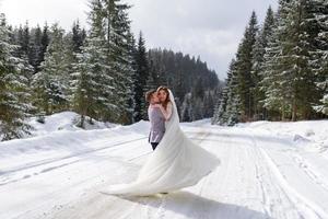 de bruidegom leidt zijn bruid bij de hand naar een eenzame oude beuk. winterse bruiloft. plaats voor een logo. foto