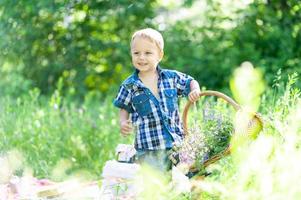 kleine schattige jongen draagt een mand met bloemen. het concept van openluchtrecreatie. foto