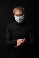 een man met een medisch masker laat zien hoe hij zijn handen moet behandelen met een ontsmettingsmiddel. coronavirus bescherming. foto
