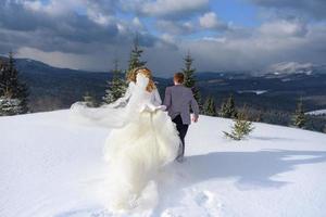 de bruidegom leidt zijn bruid bij de hand naar een eenzame oude beuk. winterse bruiloft. plaats voor een logo. foto