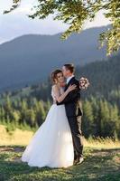 huwelijksfotografie in de bergen. de bruid en bruidegom knuffelen stevig. foto