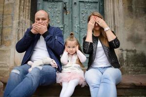 ouders en hun dochter zitten op de trappen van een oude kerk. foto