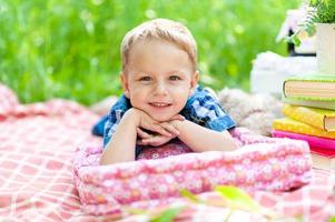 kleine schattige jongen ligt op een plaid op zijn buik, rustend op de ellebogen van zijn handen. de jongen kijkt in het frame. plaats voor een logo. foto