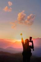 reiziger vrouw steekt hand op voor haar succes met zonsondergang op de natuurlijke achtergrond van bergen. foto