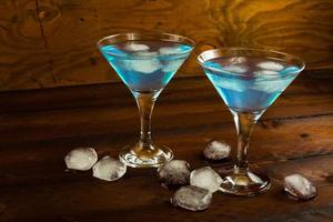 twee glazen blauwe cocktail binnen op donkere houten achtergrond foto