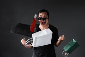 grappige online winkelverkooppromotie met dwaze uitdrukking shopaholische man met boodschappentassen naar gezicht gegooid foto