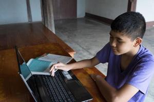 jongen die online studeert met een laptop op een bureau op het platteland foto