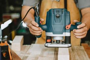 timmerman gebruikt freestrimmer om het materiaal te verwijderen en de patch op hout uit te snijden in werkplaats, doe-het-zelfmaker en houtbewerkingsconcept. selectieve focus foto