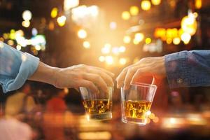 proost gerinkel van vrienden met bourbon whisky drankje in feestavond na het werk op kleurrijke achtergrond foto