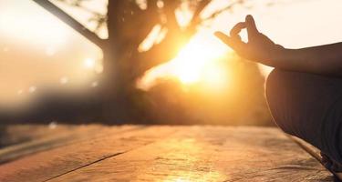 hand van vrouw die meditatie yoga beoefent op de natuur bij zonsondergang foto