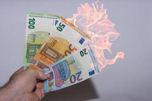 hand met veel brandende eurobiljetten inflatie in de financiële wereld foto