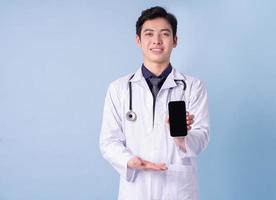 portret van jonge Aziatische mannelijke arts op blauwe achtergrond foto