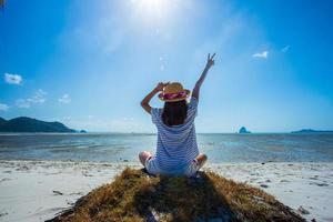 een vrouw voelt zich gelukkig zittend op het strand tropische uitzicht op thailand. foto