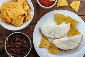 tortilla en chips in kom met salsa en bonen op rustieke houten tafelblad weergave foto