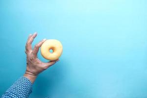 hand met verse donuts op lichtgroene achtergrond bovenaanzicht foto