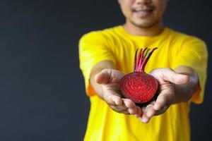 bijgesneden opname van een man die lacht met een half plakje rode biet in zijn hand voor een concept van een gezonde levensstijl foto